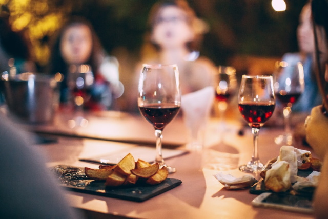 People around a table with glasses of red wine in the foreground